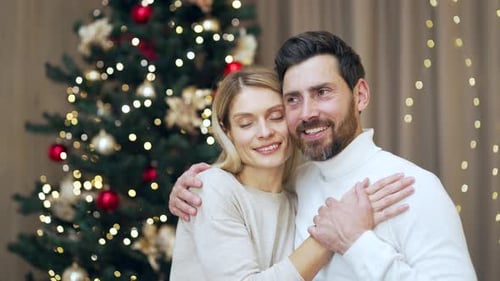 Married couple hugs on Christmas Eve or New Year holidays in cozy house indoors at home Evening.