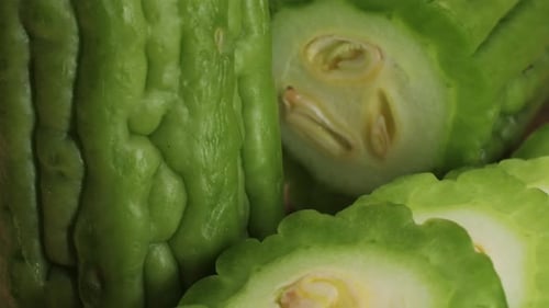 Une gourde amère, un légume souvent utilisé comme ingrédient en cuisine, est posée sur une table en bois.