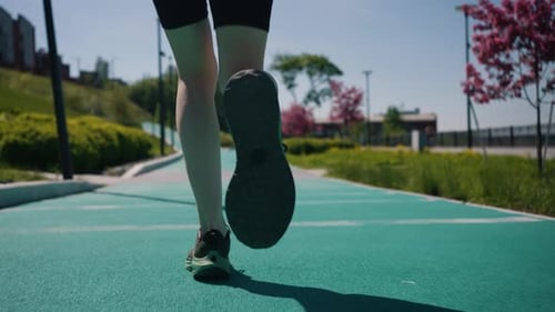 Professional Runner Practicing Smooth Stride Technique Along Curving Green Track Urban Park Setting
