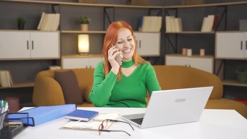 Woman Talks on Phone, Uses Laptop at Desk