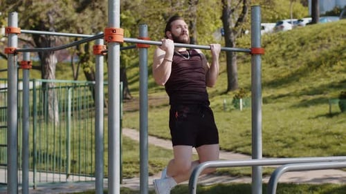 Athletischer libanesischer Mann in Sportkleidung macht Klimmzugübungen an der horizontalen Stange und pumpt den Rücken auf