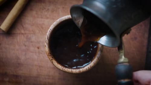 Pouring Turkish Coffee From Cezve Into Wooden Cup Close Up Top View