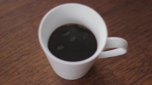 Gießen Sie schwarzen frischen Kaffee in eine weiße Tasse, Nahaufnahme