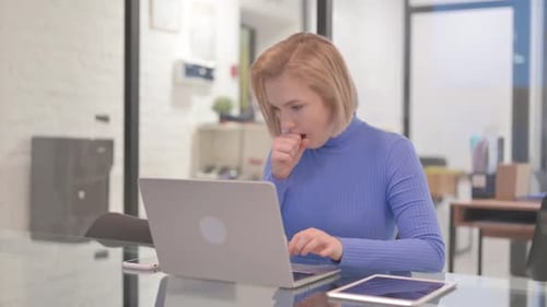Coughing Young Woman Using Laptop in Office