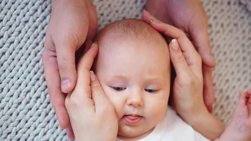 Close Up of Baby Surrounded by Parents Hands