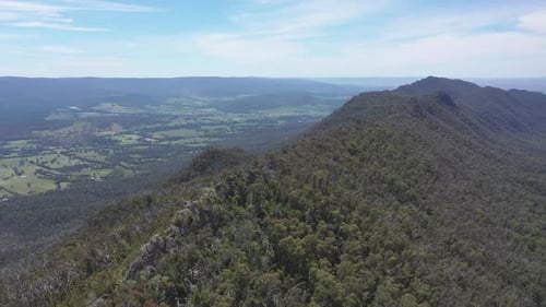 Aerial approaches sharp Razorback Ridge high above green valley below