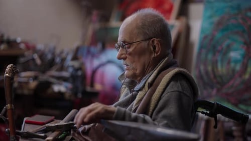 Senior Elderly Master Jeweler in Wheelchair Works in a Workshop