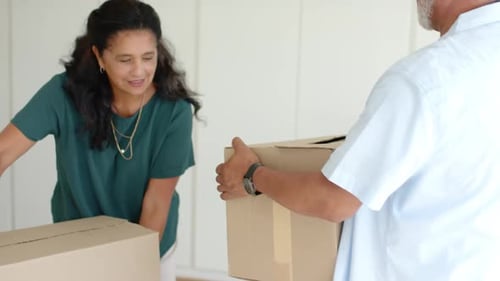 African American couple packing cardboard boxes on white cloth at home, lifting boxes for move