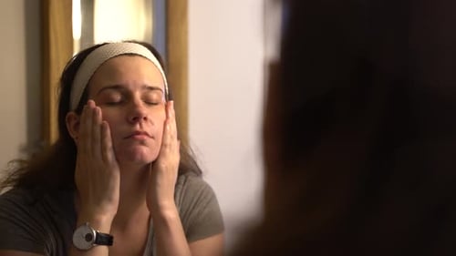 Junge Frau kümmert sich im Badezimmer um ihr Gesicht 4K