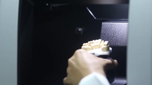Dental technician using equipment to produce denture
