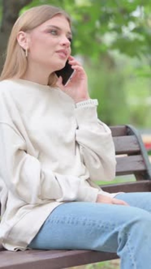 Smiling Woman Talking on Phone on Park Bench