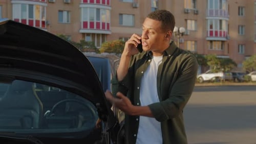 Man Talking on Phone Near Car with Open Hood