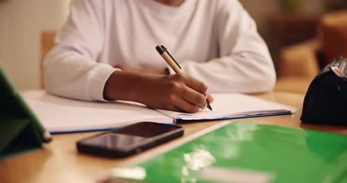 Student Writing in a Notebook at a Desk
