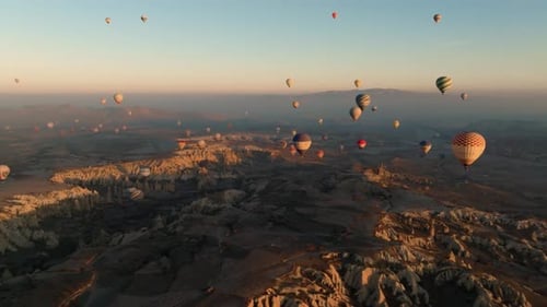 Drone view of colorful balloons floating over Love Valley with elongated chimney like rock formation