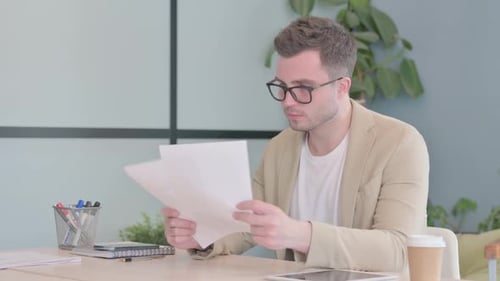 Excited Man Celebrates Reading Document at Workplace