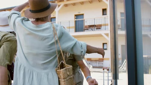 Des amies âgées s'embrassent avec des valises sur la terrasse ensoleillée de l'hôtel