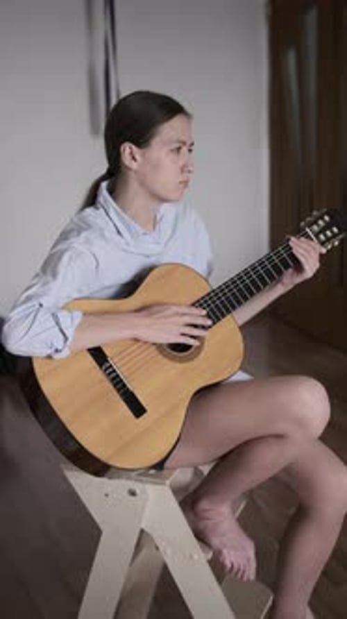 Young Woman Plays Acoustic Guitar Indoors