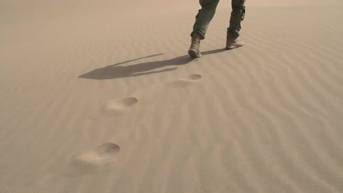 Person Walking Across Sand Dune Leaving Footprints
