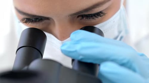 Scientist Viewing Sample Through Microscope in Laboratory