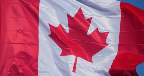 Canadian Flag Waving Against Clear Blue Sky