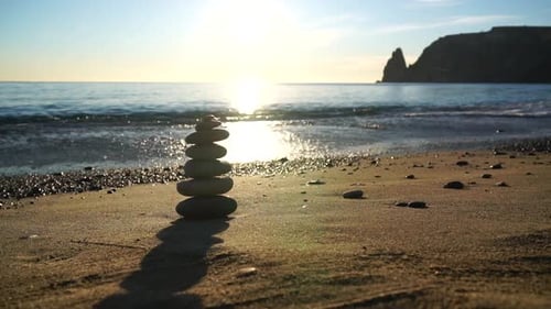 Pyramid Stones on the Seashore with Warm Sunset on the Sea Ocean Background