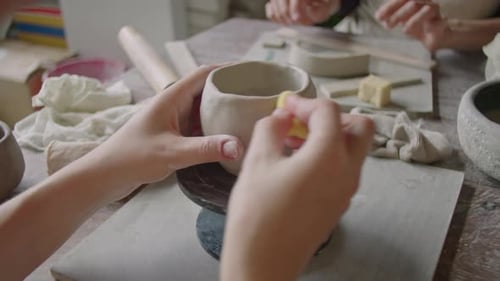 Hands Smoothing Pottery with Sponge in Studio