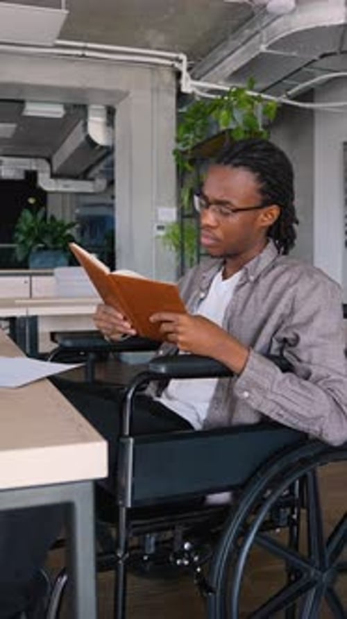 African American Student in a Wheelchair Reading in Classroom