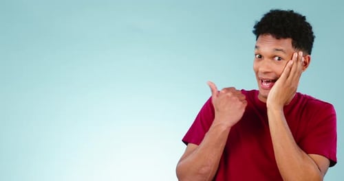 Smile, space and a man pointing to secret news on a blue background in studio for information