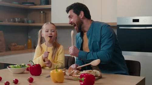 Cheerful Father and Daughter Singing in Kitchen