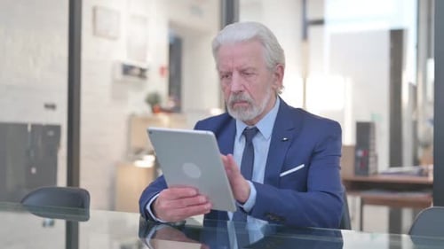 Senior Businessman Uses Tablet Device in Modern Office
