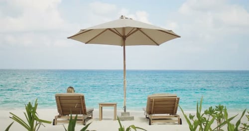 Back View of Woman Sunbathing on a Beach, She's Lying on the Deck Chair with a Beautiful Sea View.