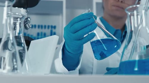 Researcher Holds Blue Liquid in Scientific Laboratory