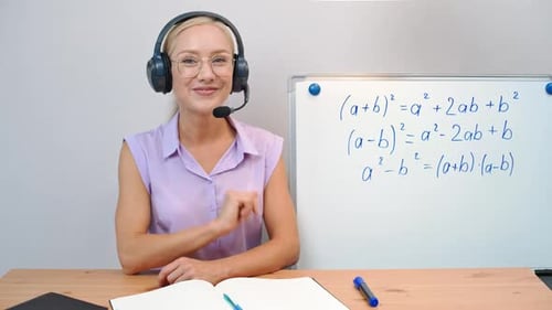 Woman Explains Math Formula at Desk With Whiteboard