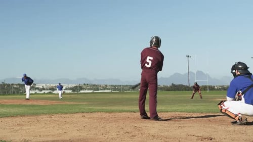 Playing baseball, batter in maroon uniform preparing to hit pitched ball
