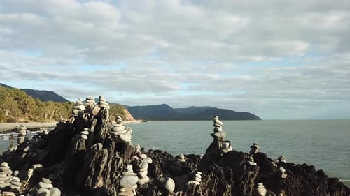 Aerial: Drone flying low around stacks of rock cairns next to the ocean in Far North Queensland, Aus