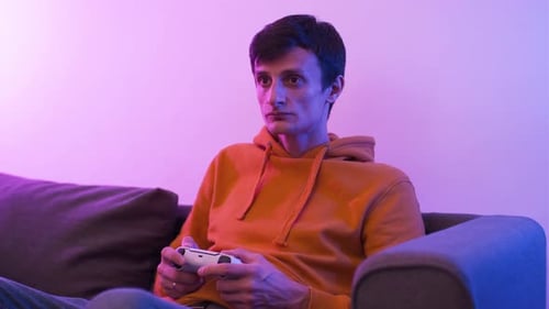 Man Gaming with Controller on Couch at Home