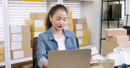 Woman Using Laptop With Shipping Boxes in Background