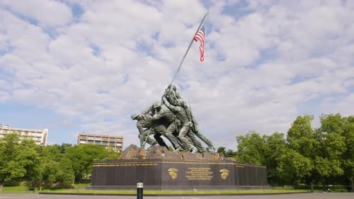 The camera dollys around the US Marine Corp War Memorial with wind blowing the American flag with no