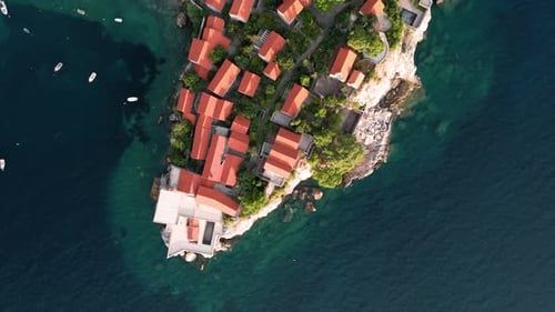 Birdview on Sveti Stafan with houses of the luxury resort revealing the island, pathway and beach in