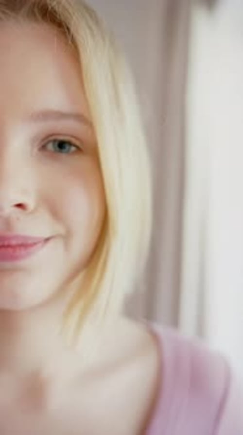 Vertical video of portrait of caucasian female teenager with blond hair at home, slow motion