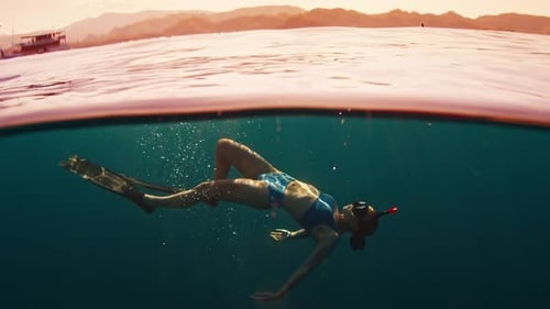 Woman Freediver Swims Underwater in the Sea at Sunset and Relaxes and Floats Beneath the Surface