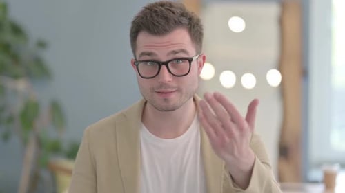 Man Smiling and Gesturing Towards the Viewer