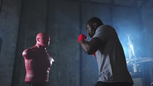 Fitness Workout in Gym Strong African Man Fighter Training Punches with Hitting Punching Bag