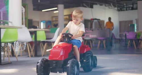 Blonde Child on Toy Tractor Indoors