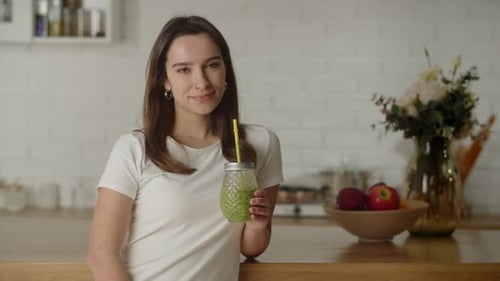 Young Woman with Healthy Green Smoothie in Kitchen
