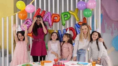 Two Mothers with a Group of Children at a Birthday Party in a Brightly Room