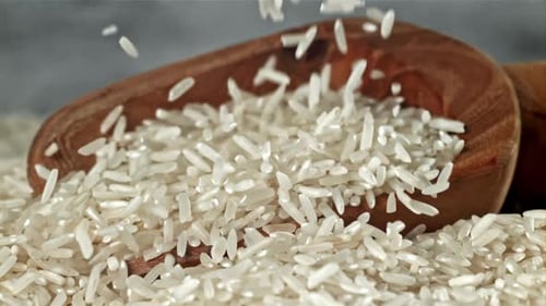 White Rice Falling Into Rustic Wooden Bowl