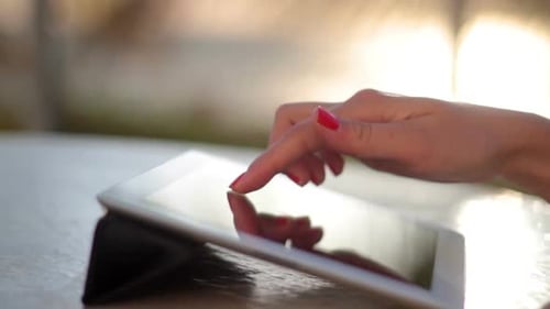 Junge Frau tippt bei Sonnenaufgang an einem schönen Strand auf Tablet
