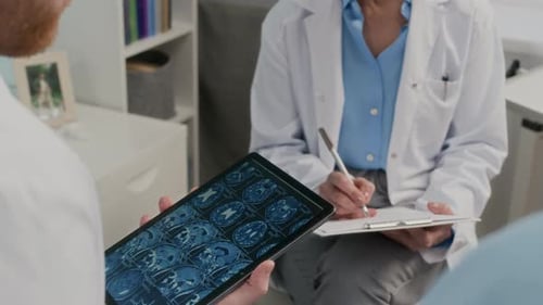 Physicians Using MRI Scan on Tablet when Discussing Treatment Plan with Patient