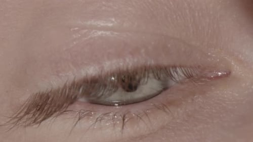 Extreme Nahaufnahme eines blauen Auges, der sich umschaut und blinzelt